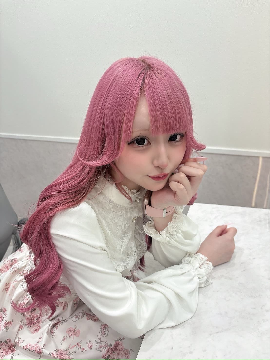 ピンクの髪で、手をほほに当ててポーズをとる、SNS用のイメージ写真